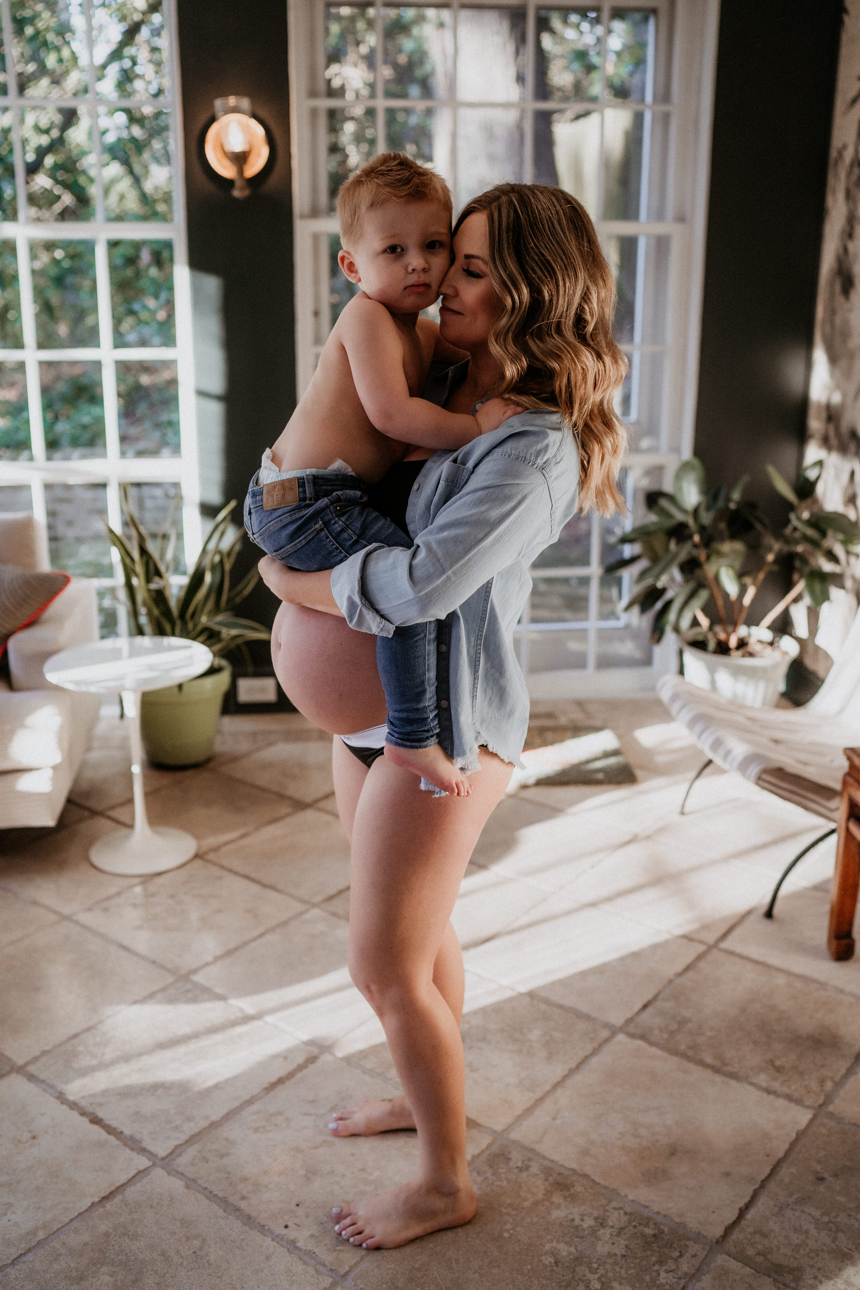 Intimate in-home maternity photography, toddler sitting on top of mothers belly
